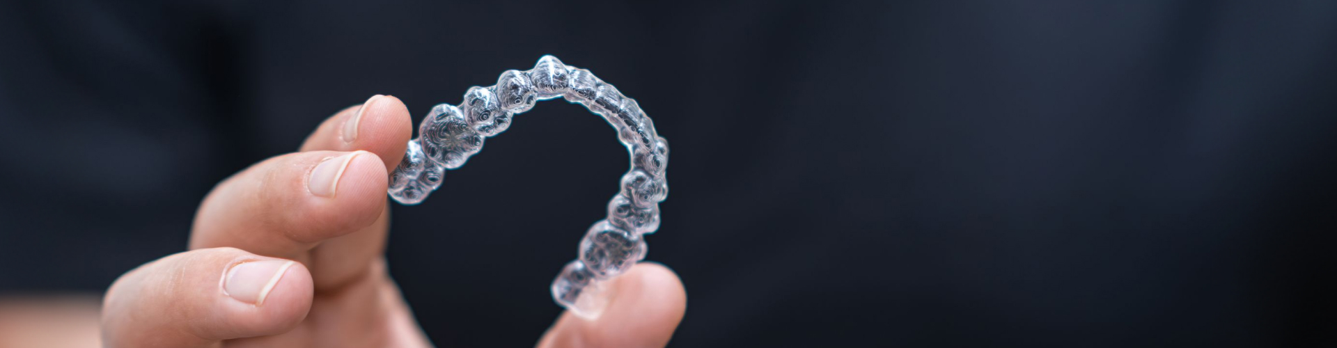 Hand holding clear aligner.